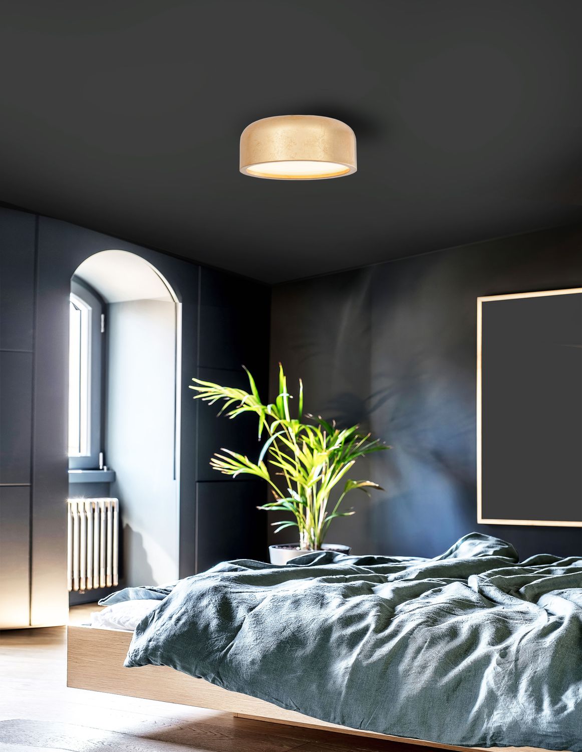 Plafonnier doré installé au plafond d'une chambre sombre et moderne