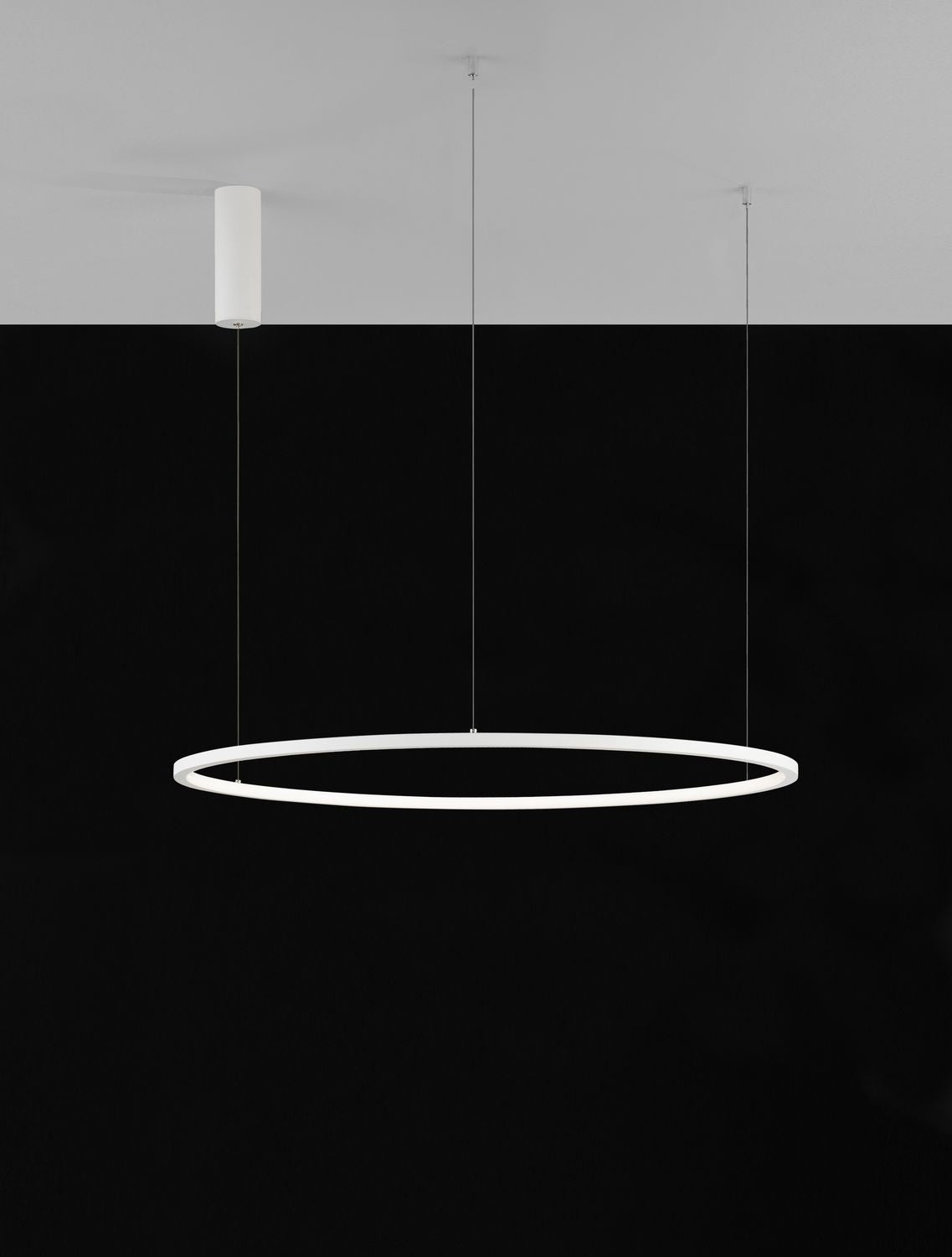 Vue de face sur fond noir, anneau LED blanc allumé suspendu par câbles