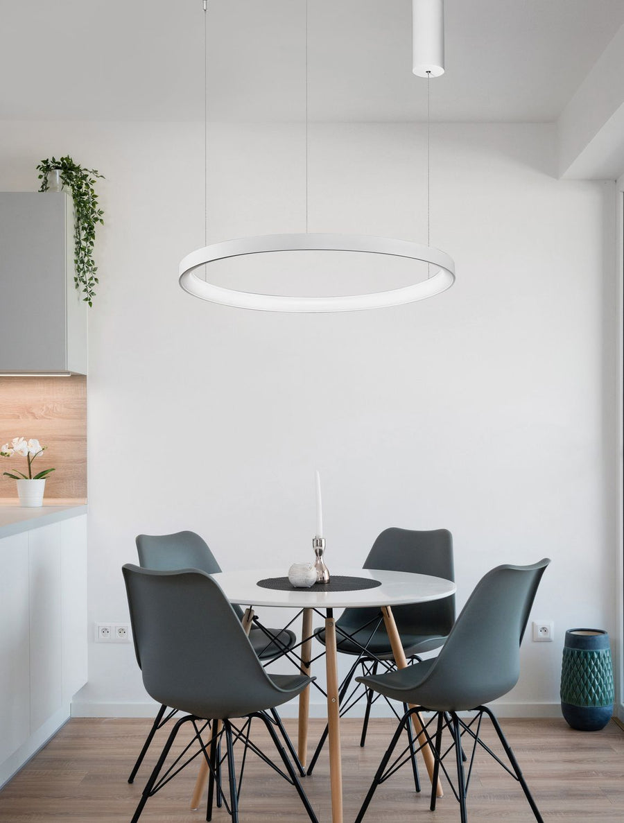Suspension anneau blanc allumée au-dessus d'une table à manger dans un intérieur clair