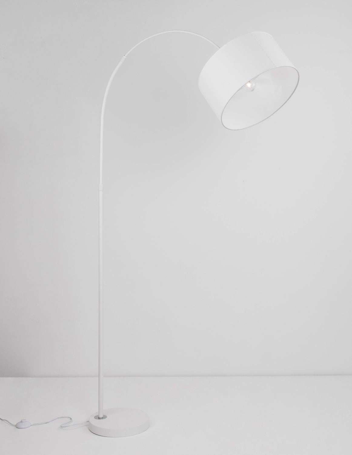 Lampadaire arc blanc avec abat-jour cylindrique en tissu, vue de face sur fond clair.