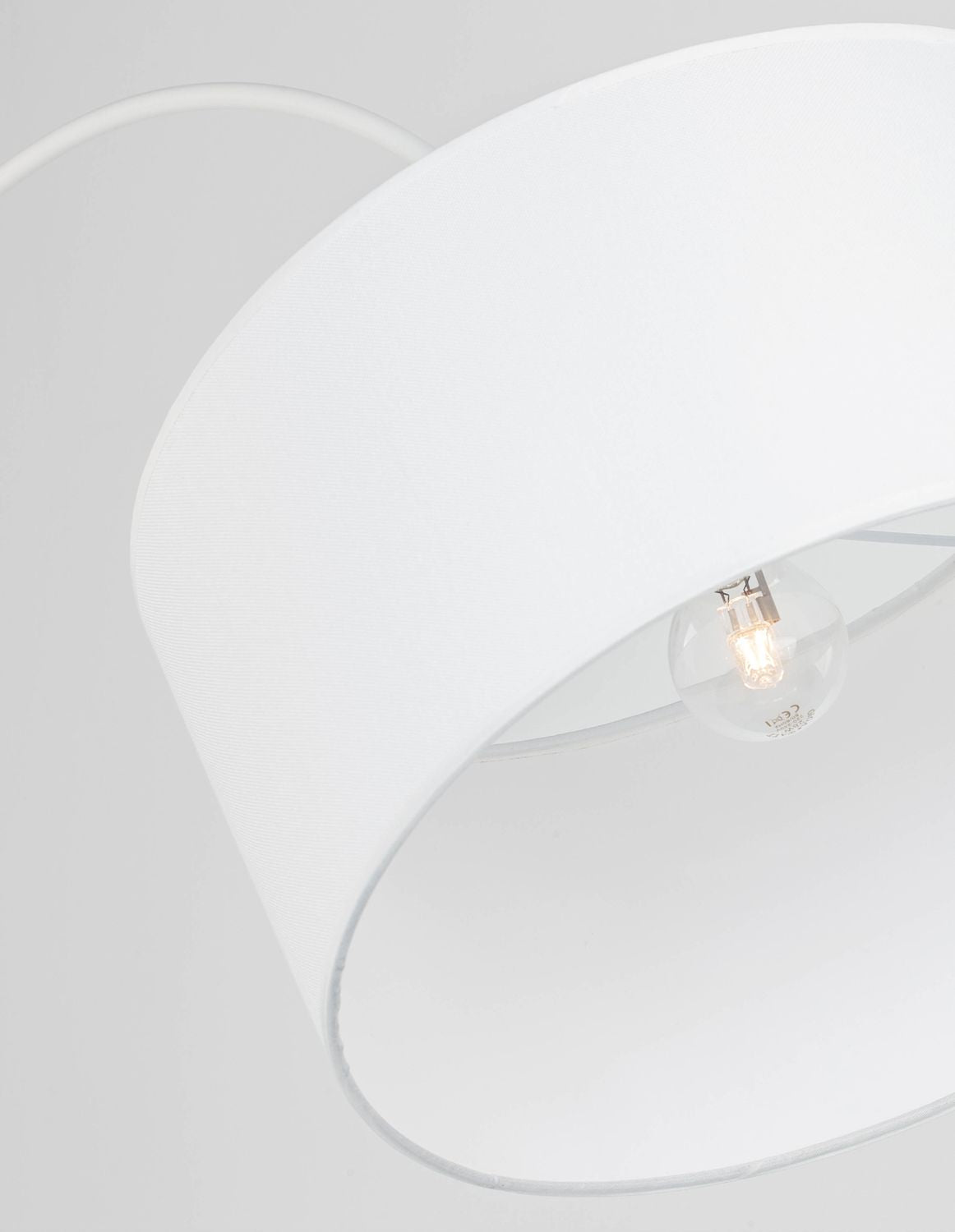 Gros plan sur la texture du tissu blanc et l'ampoule allumée à l'intérieur de l'abat-jour.