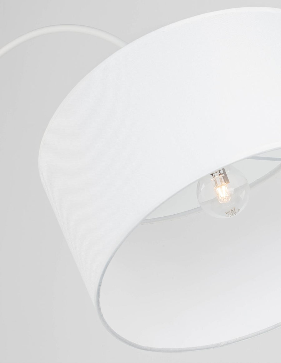 Gros plan sur la texture du tissu blanc et l'ampoule allumée à l'intérieur de l'abat-jour.