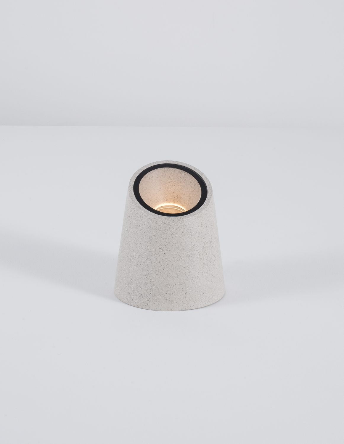 Borne blanche allumée sur fond blanc, diffusant une lumière chaude