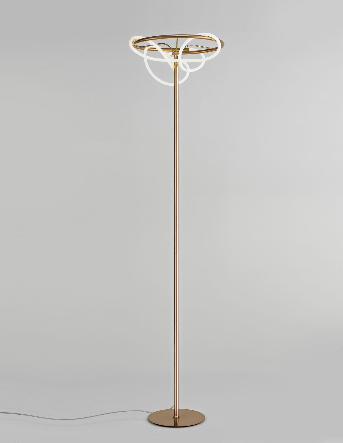 Lampadaire doré de face, tige fine et anneaux lumineux entrelacés