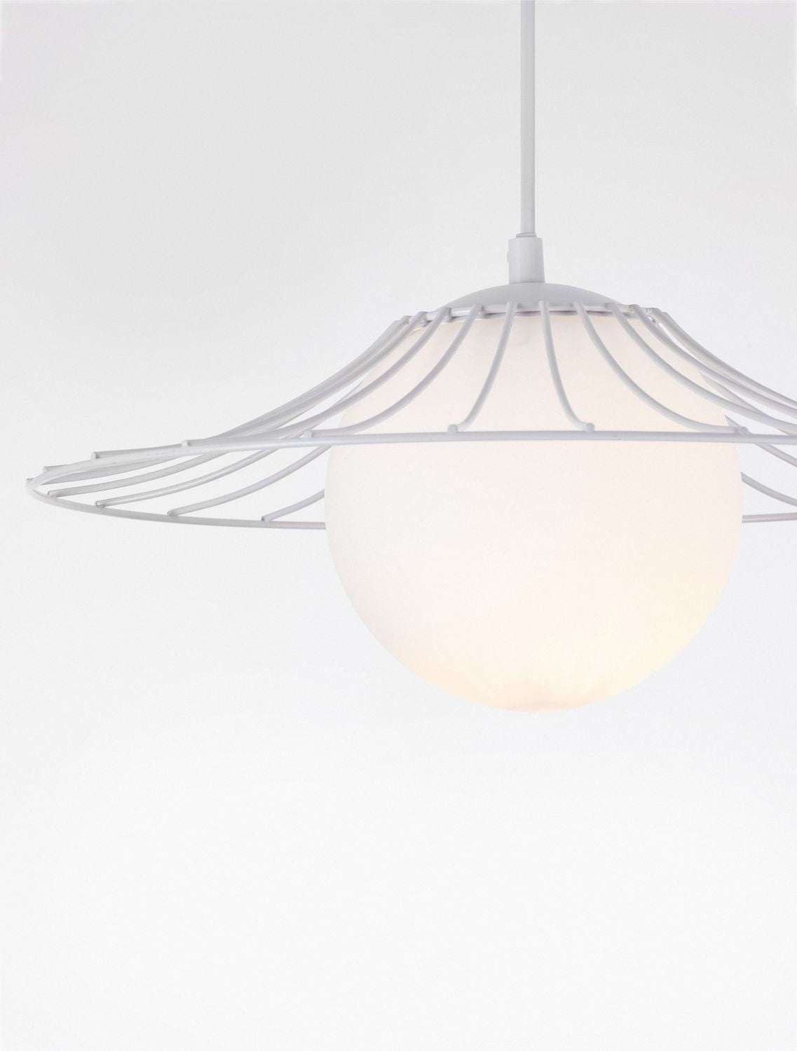 Gros plan sur la sphère de verre opalin et la cage métallique blanche