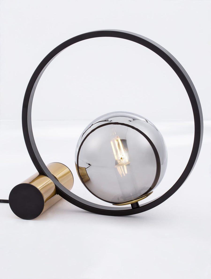 Gros plan sur la sphère en verre fumé et l'ampoule à filament dorée allumée