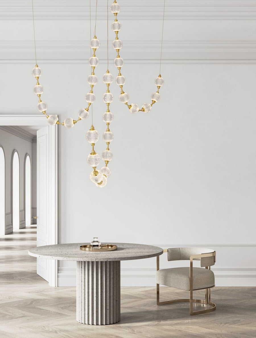 Suspension dorée à billes de verre suspendue au-dessus d'une table ronde en pierre