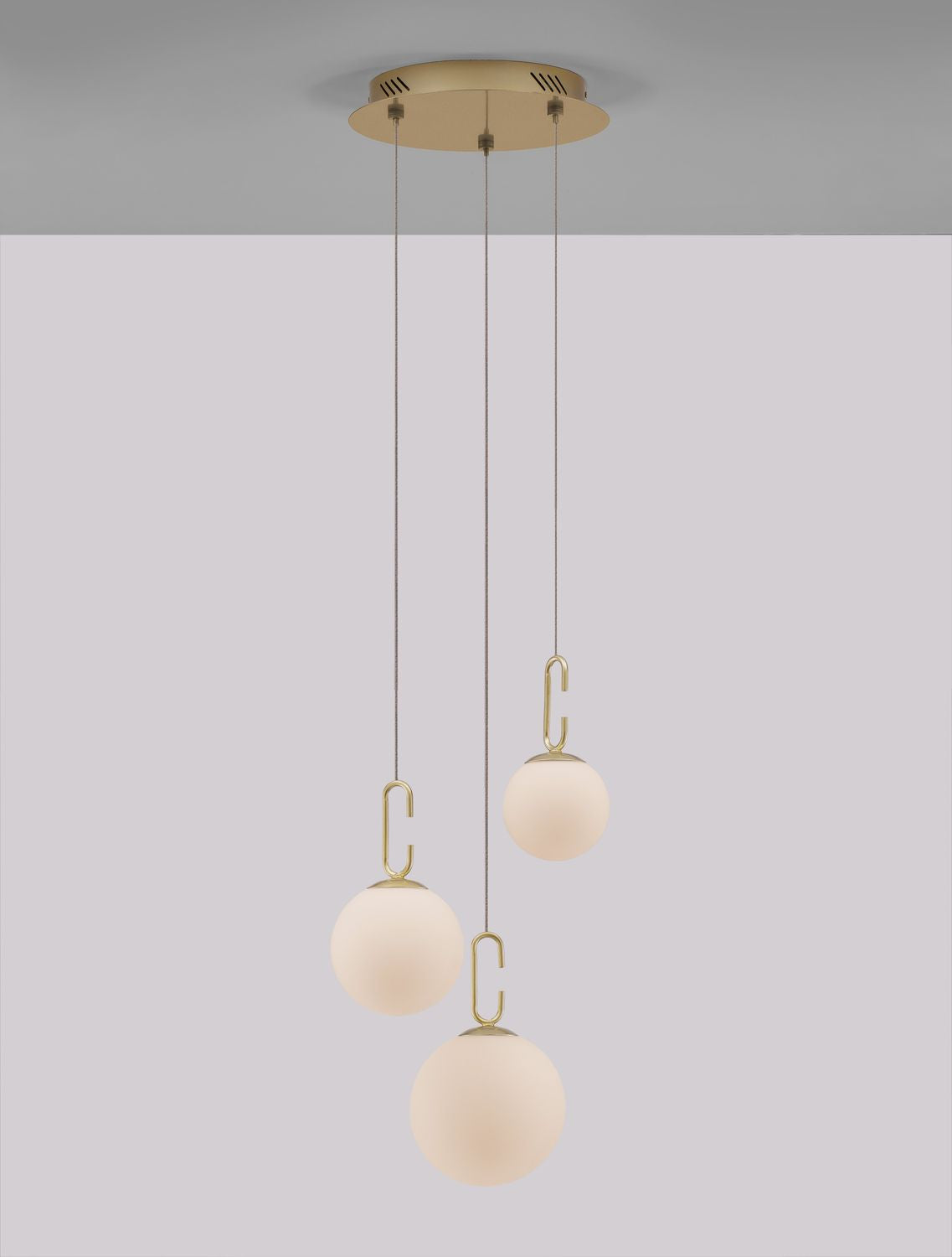 Mise en ambiance de la suspension aux trois globes blancs et crochets dorés.
