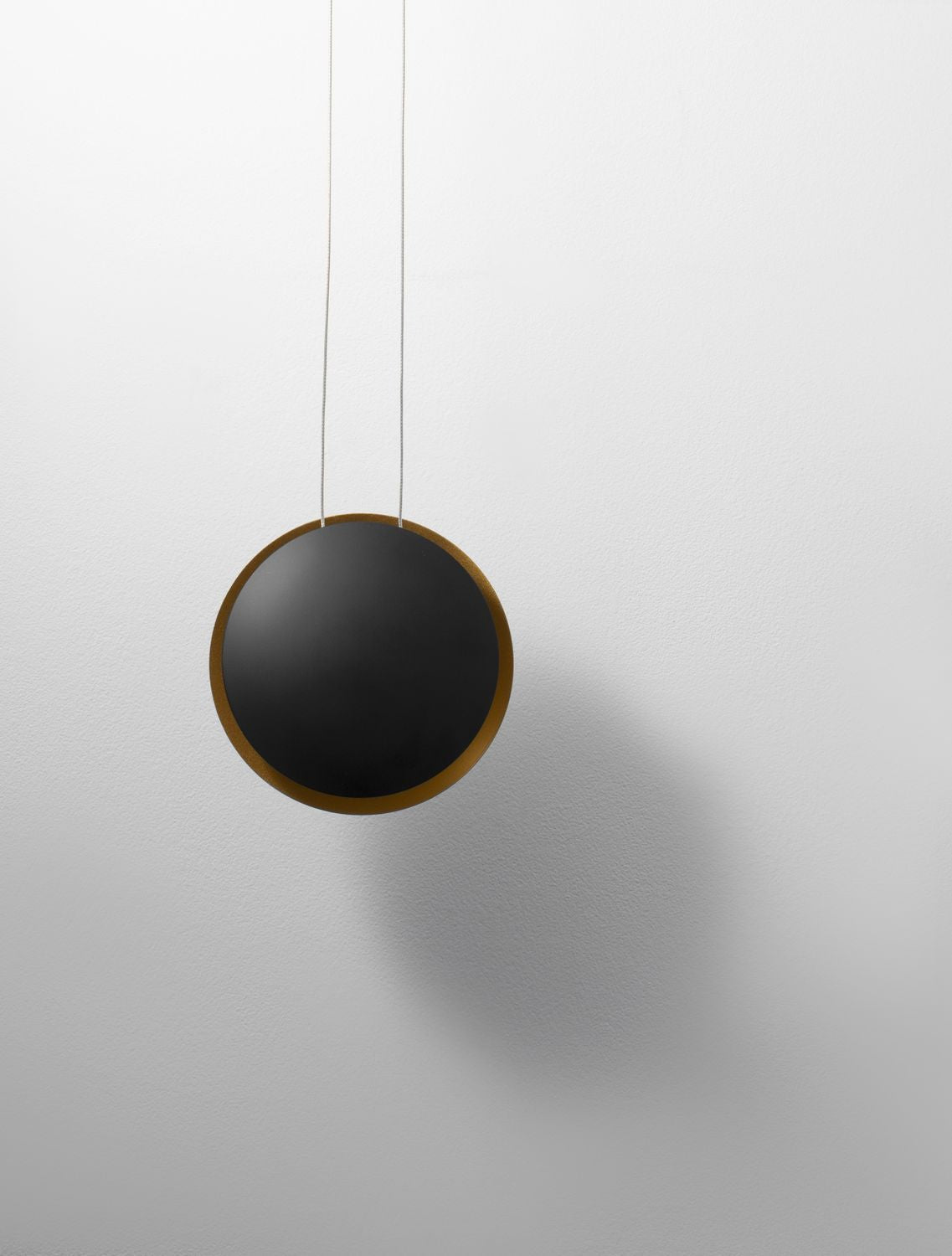 Face avant du luminaire rond noir mat avec finition dorée sur fond blanc