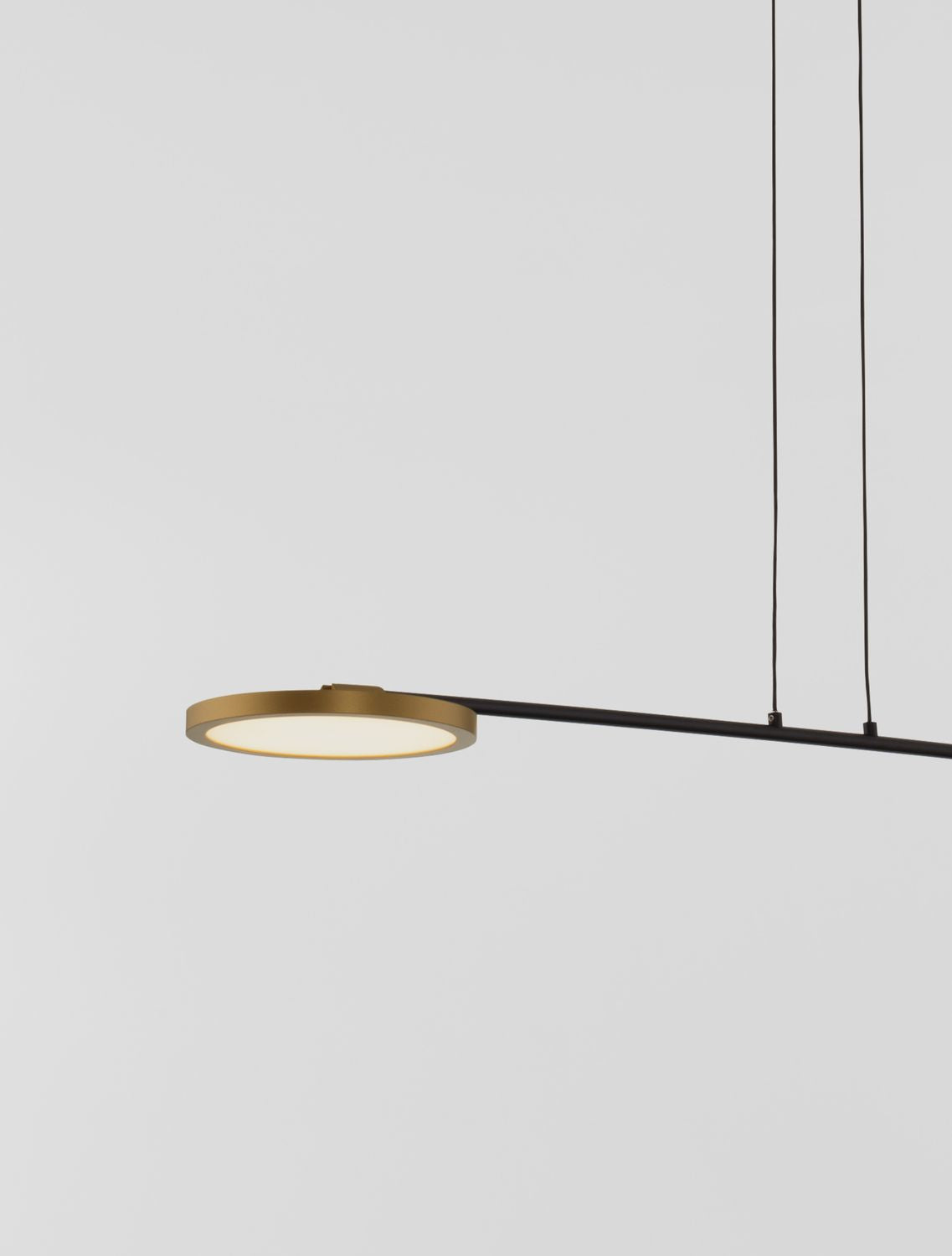 Détail d'une tête lumineuse ronde à cerclage laiton sur barre noire