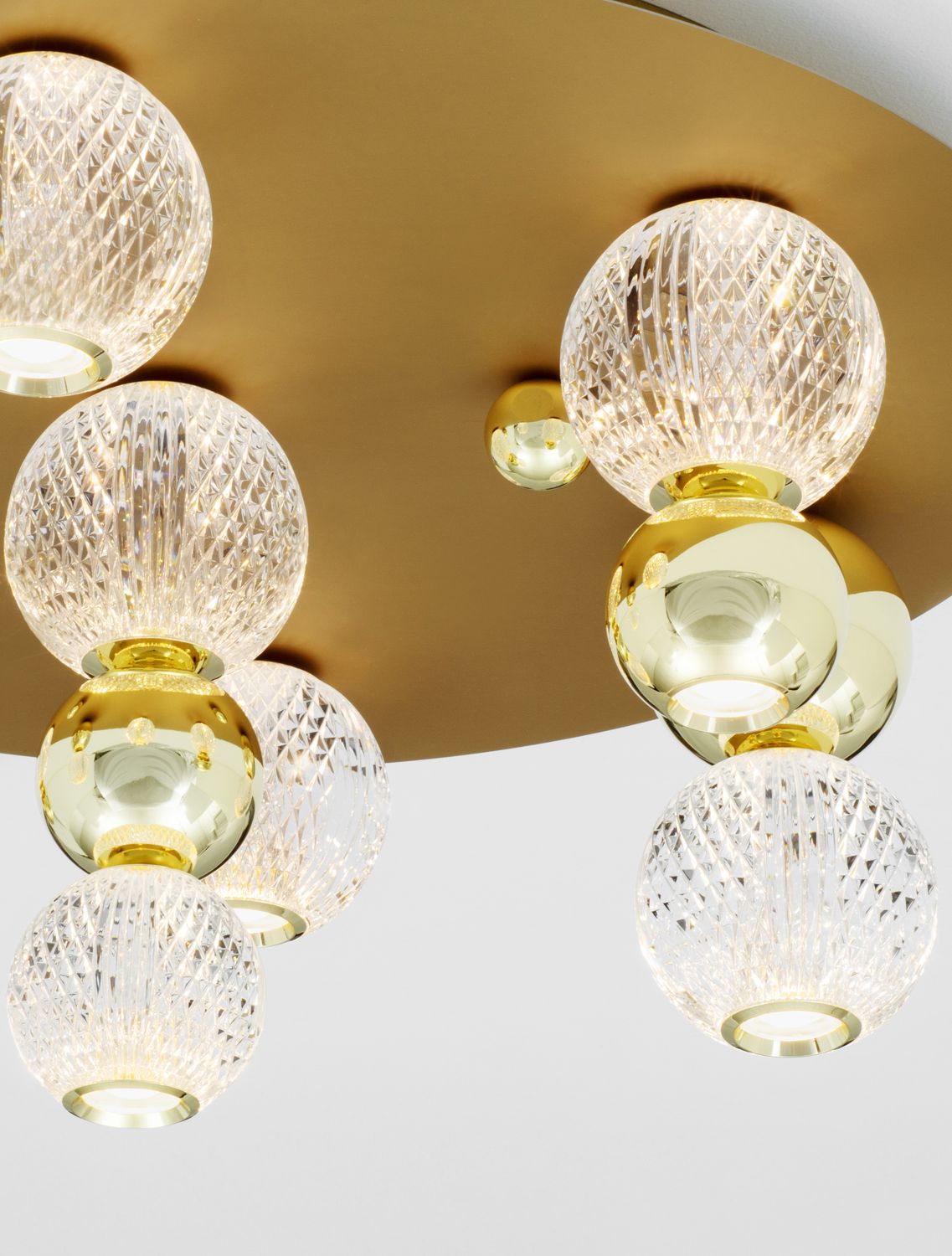 Détail rapproché de la finition dorée et des globes de verre texturés