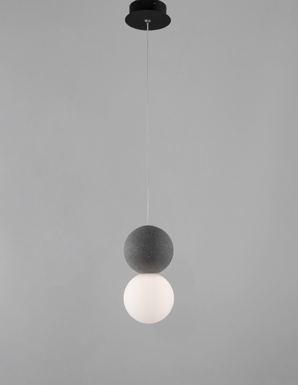 Luminaire suspendu présenté de face sur fond gris, rosace noire et câble tressé