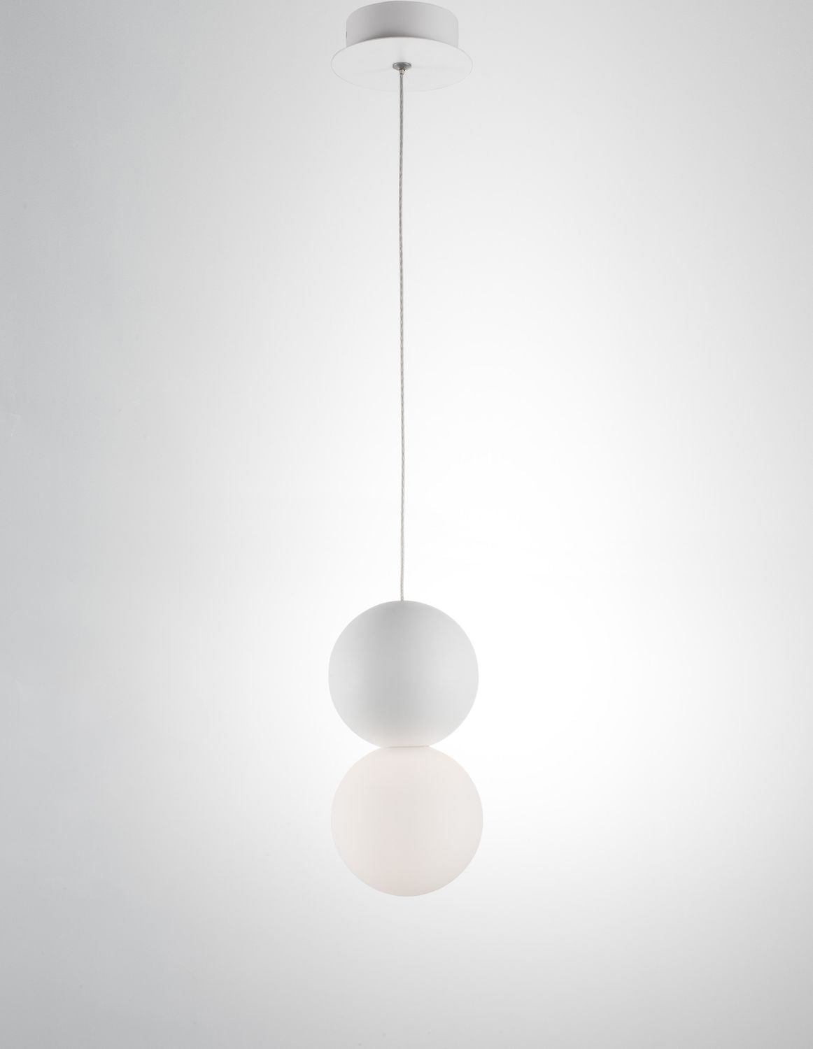 Suspension blanche présentée sur fond clair, câble fin et double sphère en verre opalin.