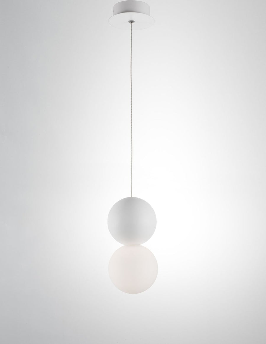Suspension blanche présentée sur fond clair, câble fin et double sphère en verre opalin.