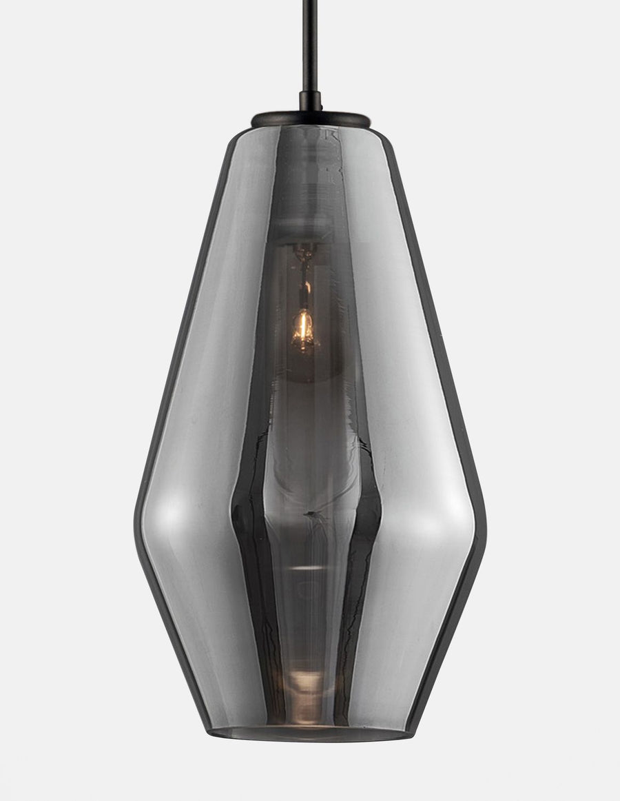 Gros plan sur l'abat-jour en verre fumé facetté et l'ampoule allumée à l'intérieur.