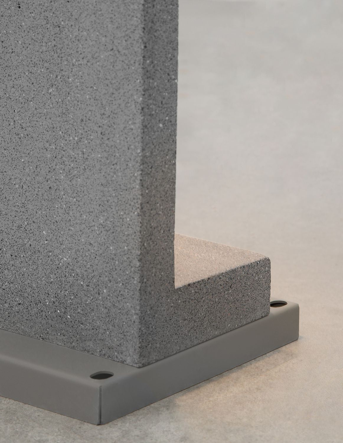 Détail de la platine de fixation et de la texture granuleuse du béton gris