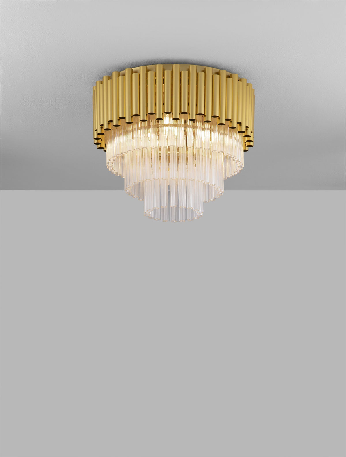 Plafonnier doré et cristal installé au plafond, lumière allumée, fond gris