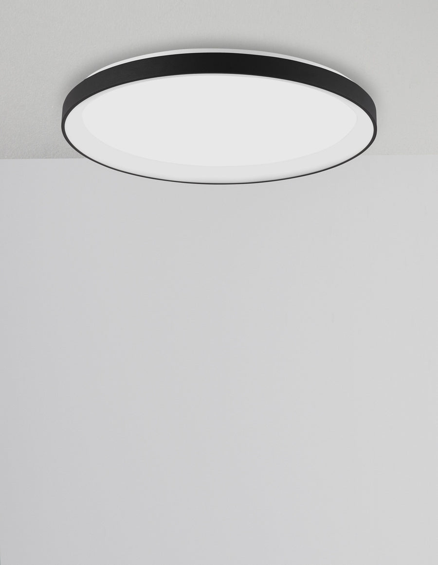 Vue en contre-plongée du luminaire circulaire fixé au plafond, bordure noire et diffuseur blanc.