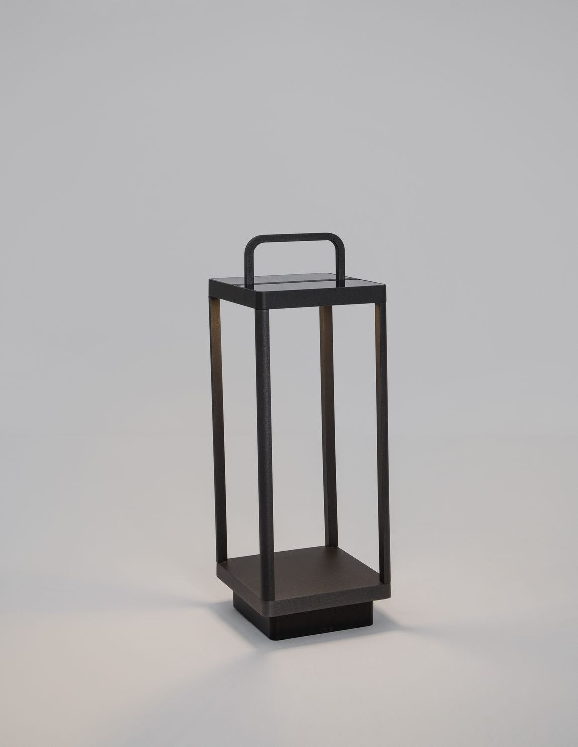 Luminaire extérieur anthracite de trois quarts sur fond gris clair, structure rectangulaire ajourée avec poignée.