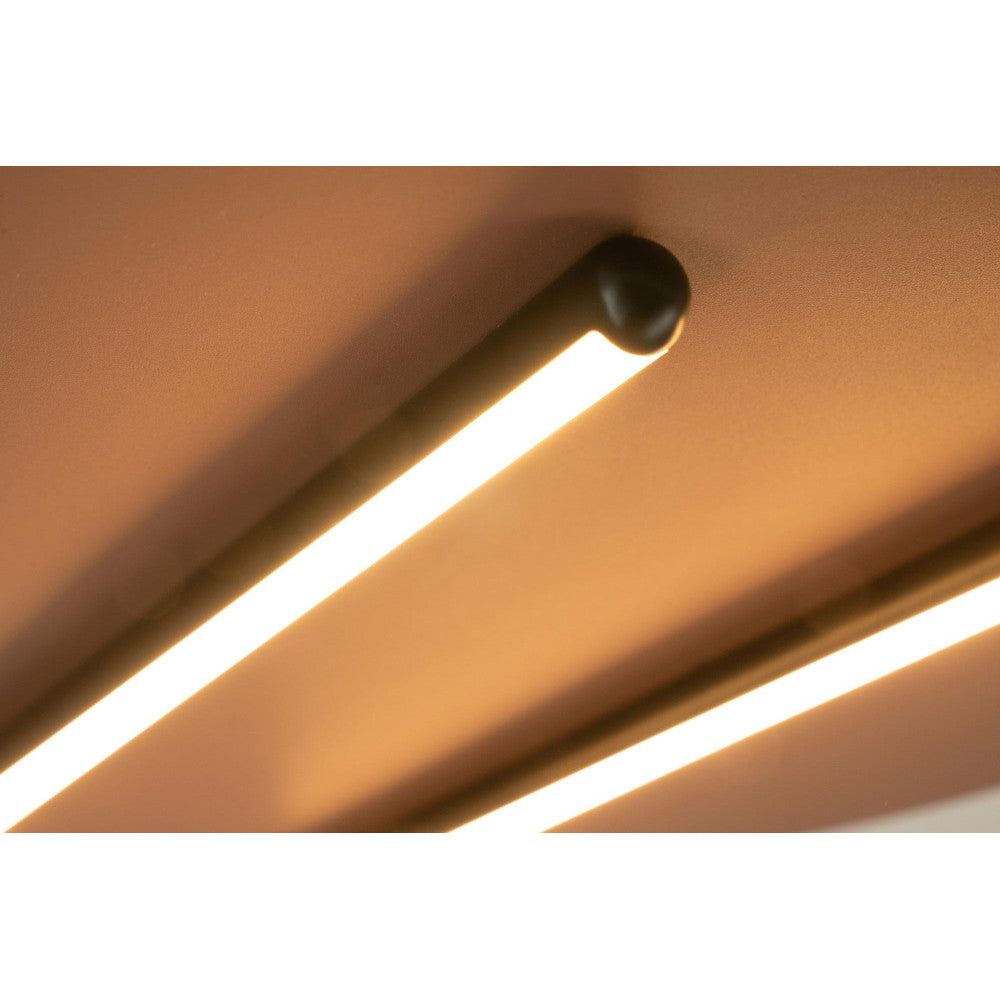 Gros plan sur un tube LED allumé, embout noir mat, lumière chaude rasante