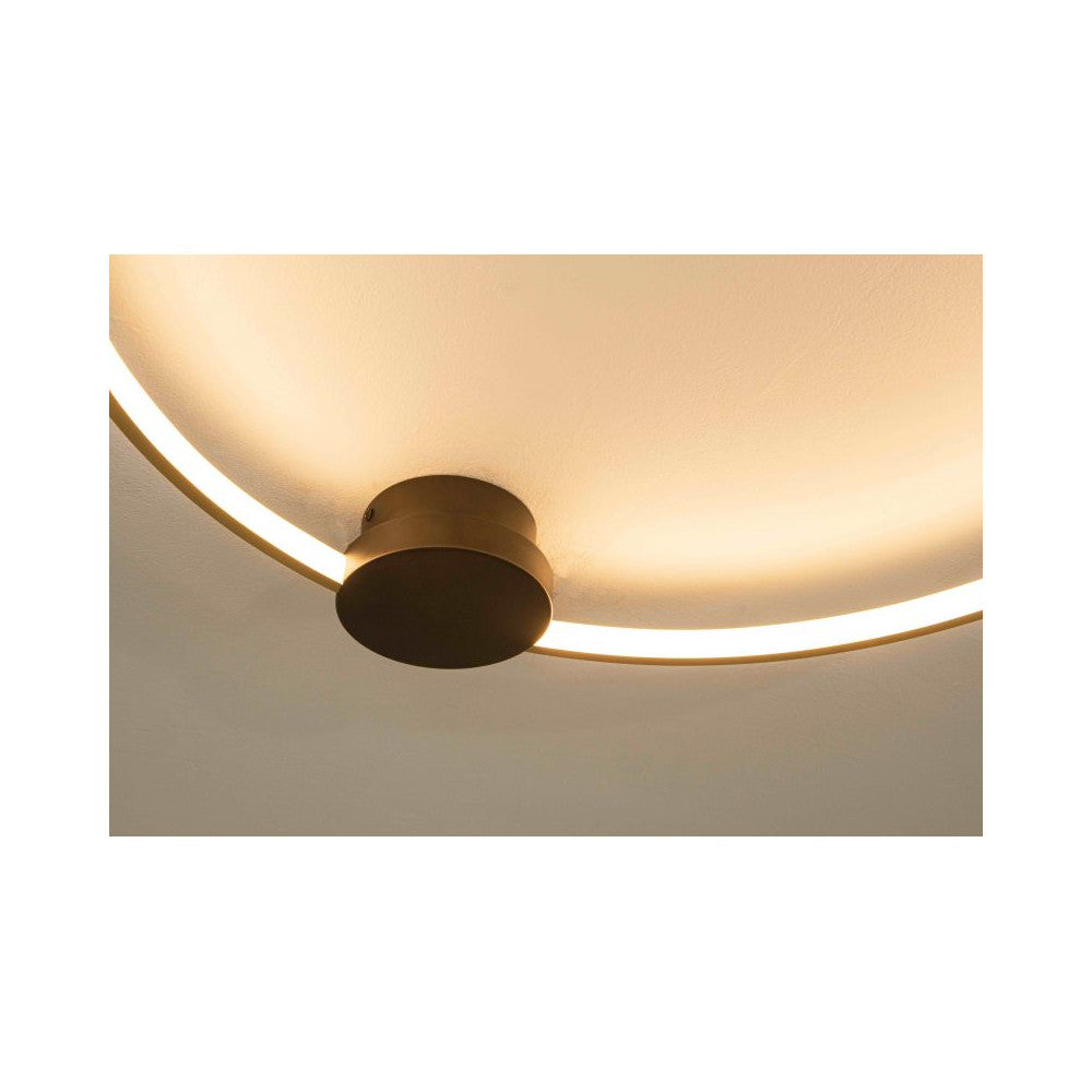 Détail du socle central noir fixé au plafond, anneau doré diffusant une lumière chaude