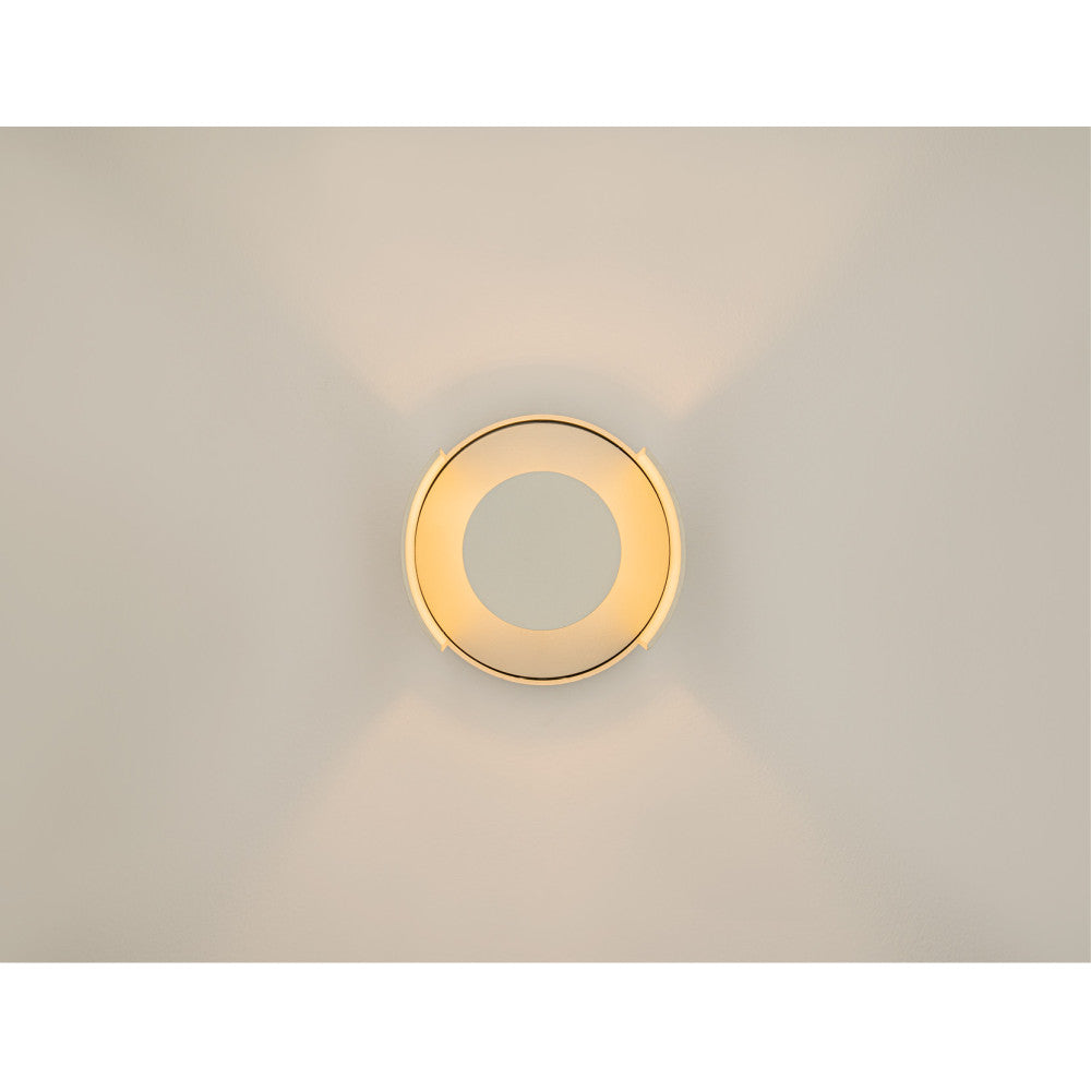 Applique allumée vue de face projetant une couronne de lumière sur mur beige