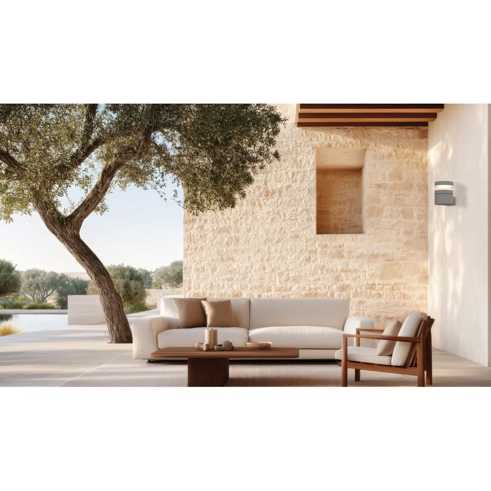 Mise en ambiance sur terrasse extérieure, applique grise fixée au mur en pierre.