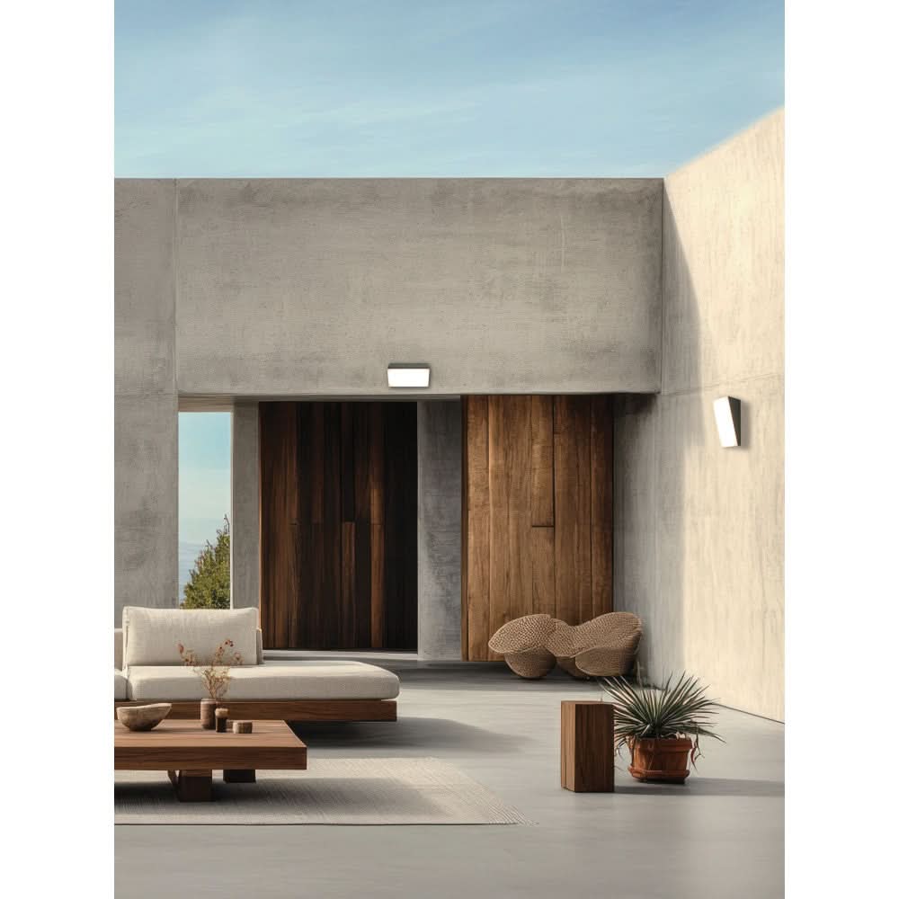 Applique extérieure éclairée sur mur béton, terrasse moderne avec mobilier et plantes.