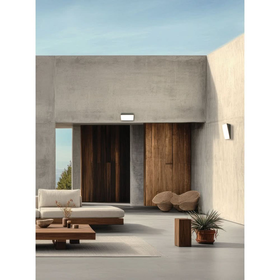 Applique extérieure éclairée sur mur béton, terrasse moderne avec mobilier et plantes.