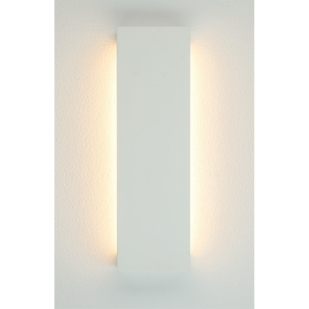 Même applique blanche installée verticalement sur un mur, éclairage direct et indirect latéral.