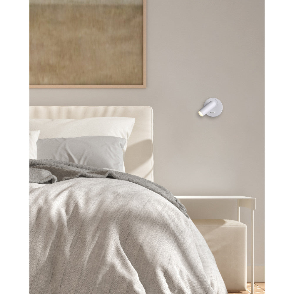 Mise en ambiance dans une chambre, applique murale blanche fixée près du lit.