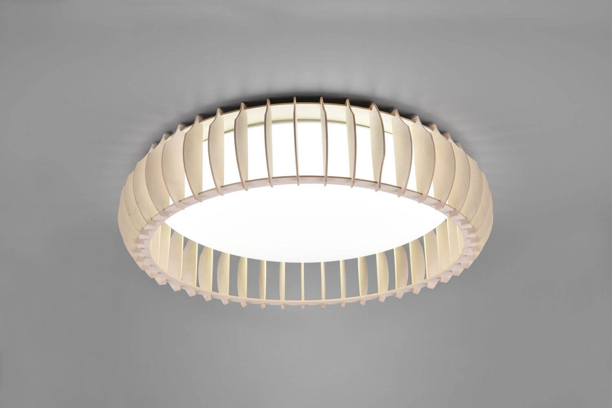 Plafonnier blanc vu de trois quarts, détail des lames incurvées et diffuseur central lumineux.
