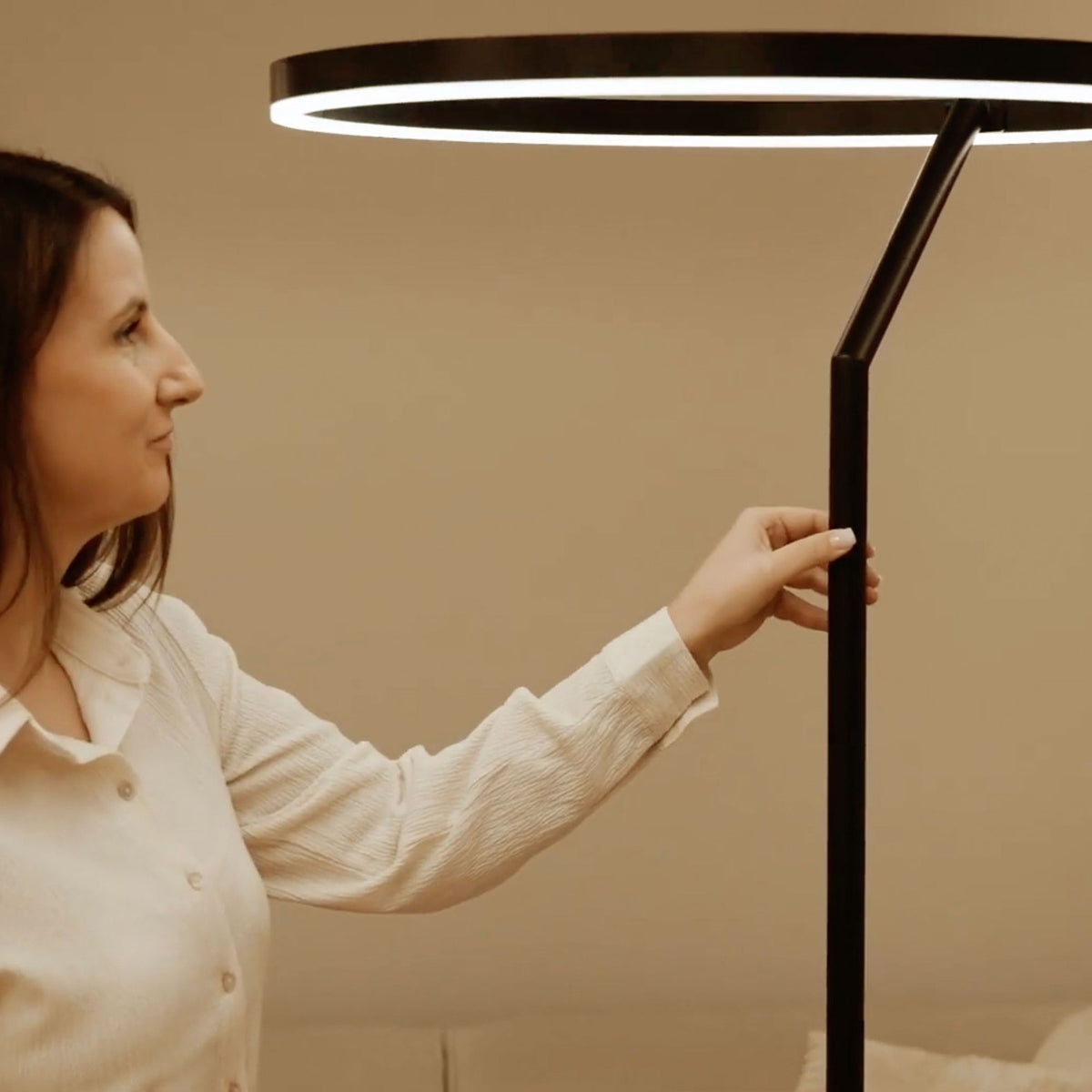 Personne réglant la hauteur du lampadaire, anneau LED éclairé au-dessus d'elle.