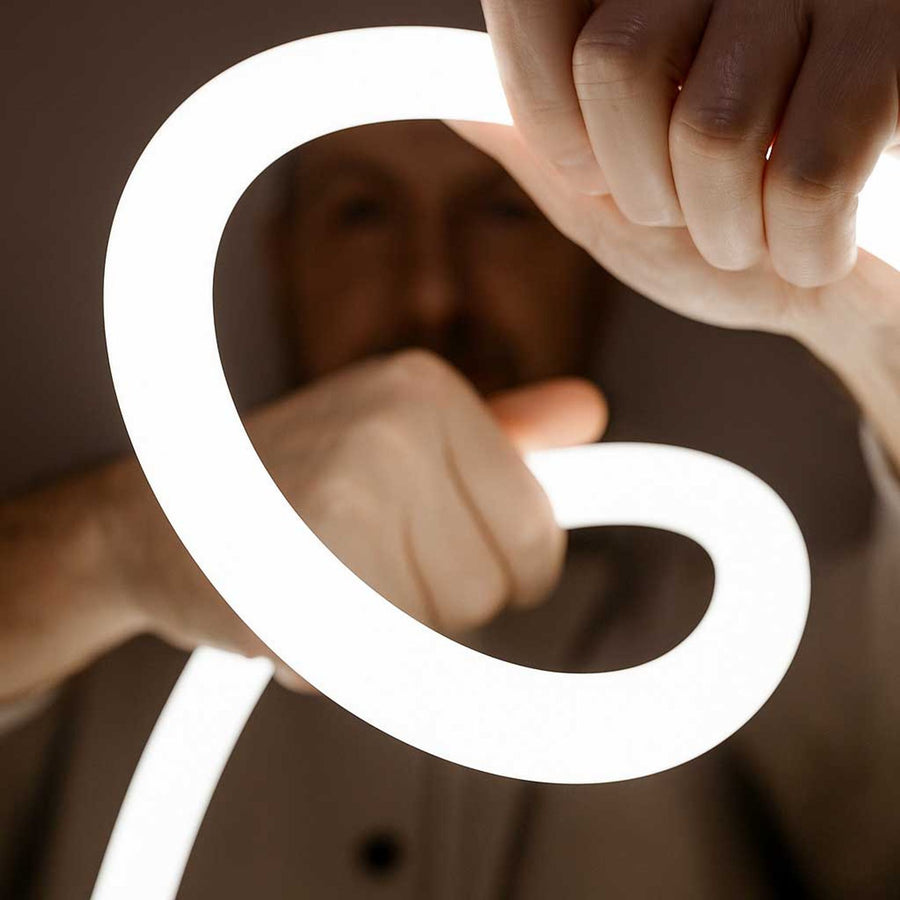 Détail montrant une main courbant le tube lumineux flexible et souple.