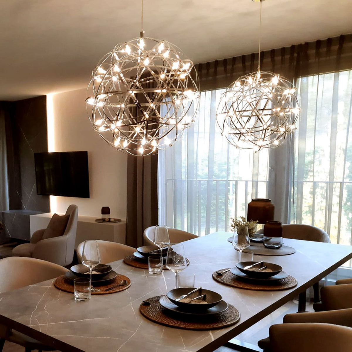 Ambiance salle à manger avec deux suspensions boules dorées allumées au-dessus de la table.