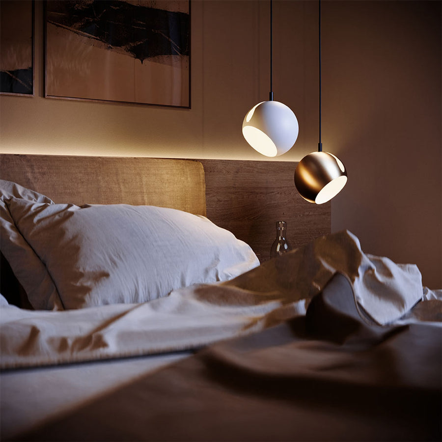 Deux petites suspensions boule blanche et dorée au-dessus d'un lit froissé