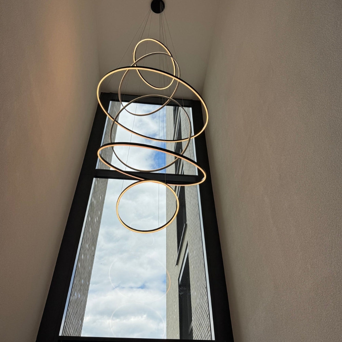 Grande suspension aux nombreux cercles dorés superposés dans une cage d'escalier