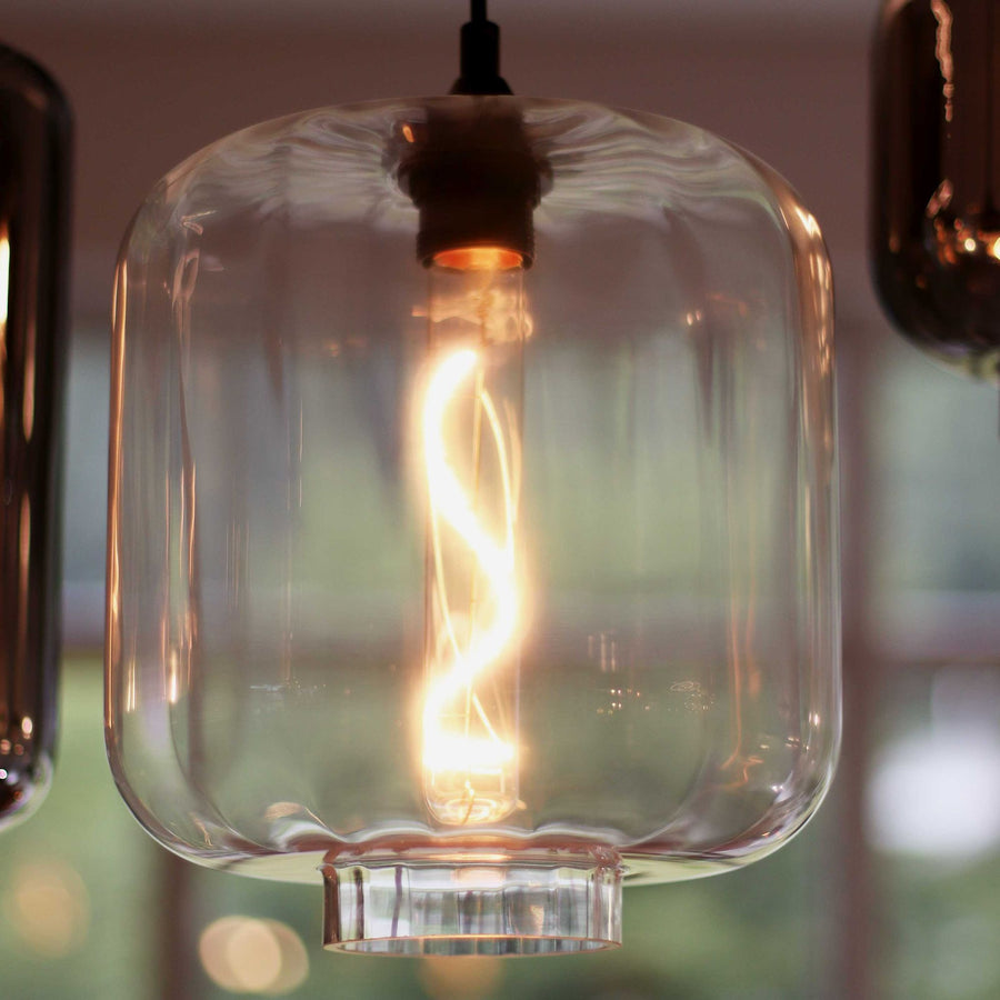 Gros plan d'un verre transparent avec ampoule à filament spiralé allumée.