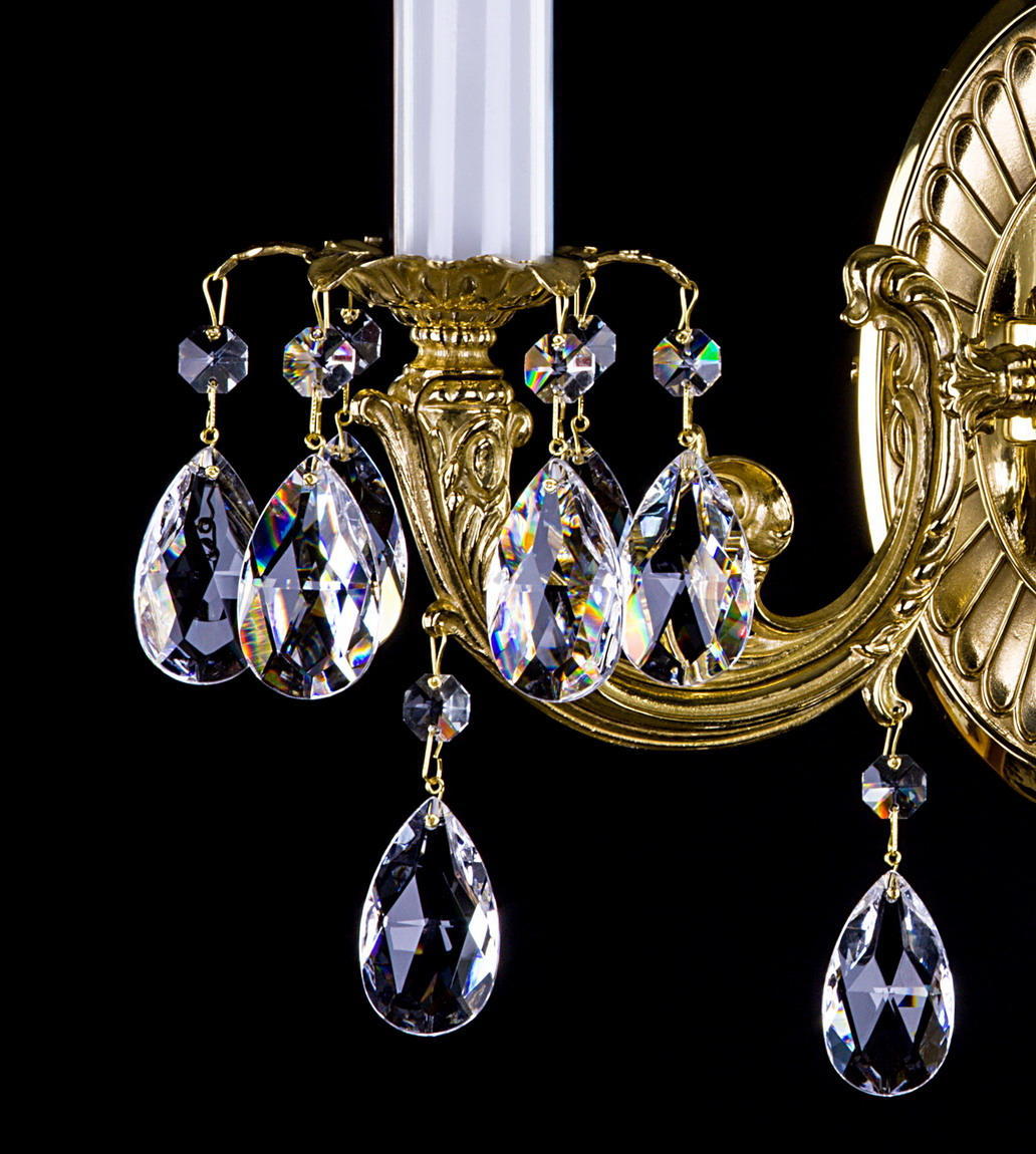 Détail d'un bras doré avec pendants en cristal taillé en goutte