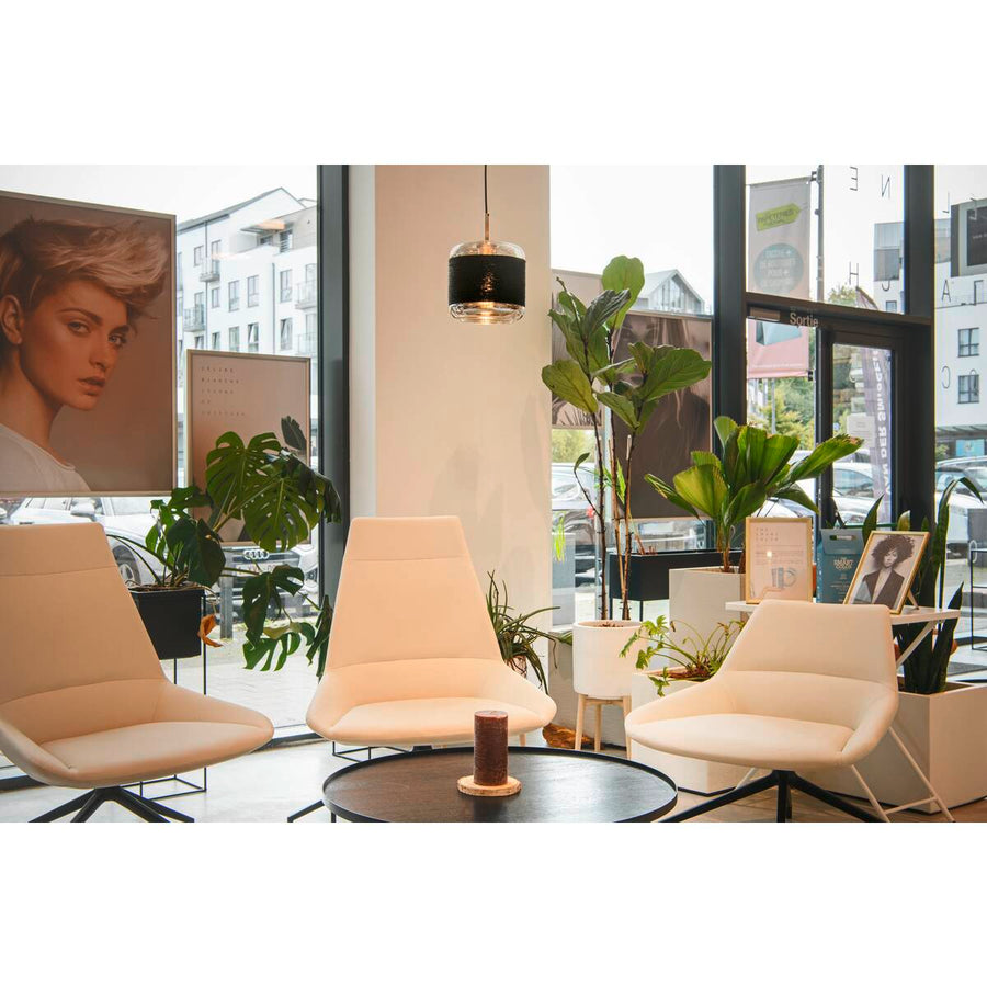 Suspension installée dans un espace salon avec chaises blanches et plantes vertes.