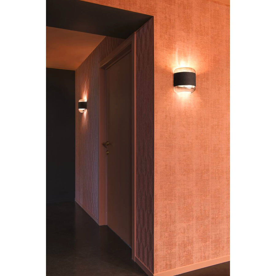 Couloir sombre éclairé par deux appliques murales projetant une lumière orangée sur les murs