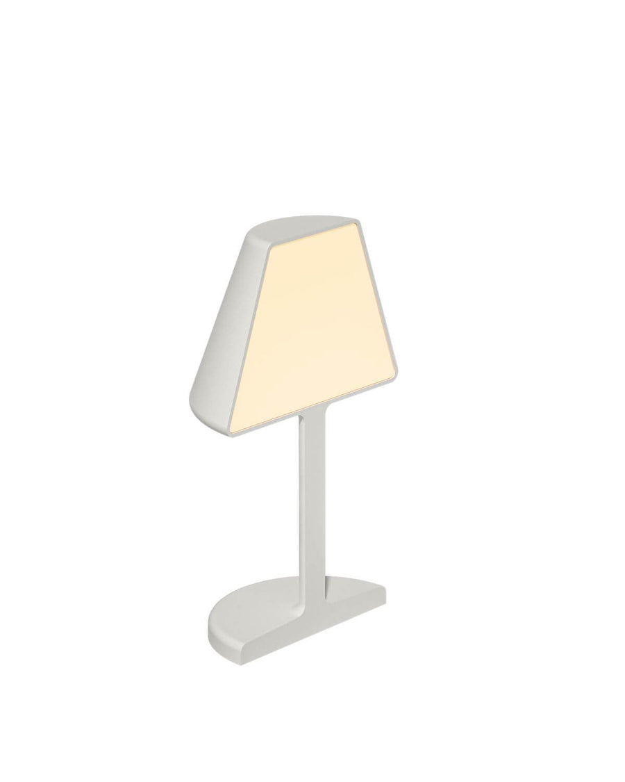 Lampe blanche inclinée, abat-jour conique allumé, fond neutre, vue de trois quarts.