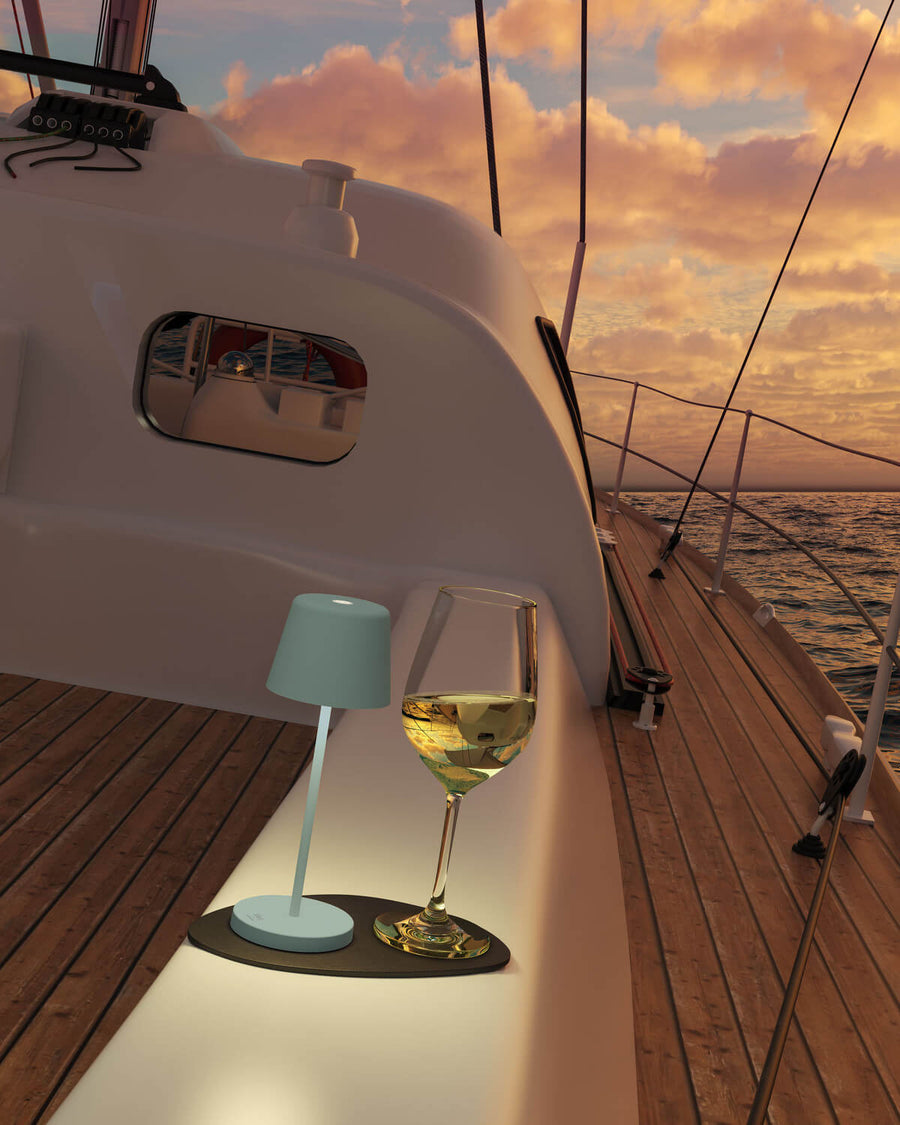 Lampe posée près d'un verre de vin blanc sur le pont d'un voilier