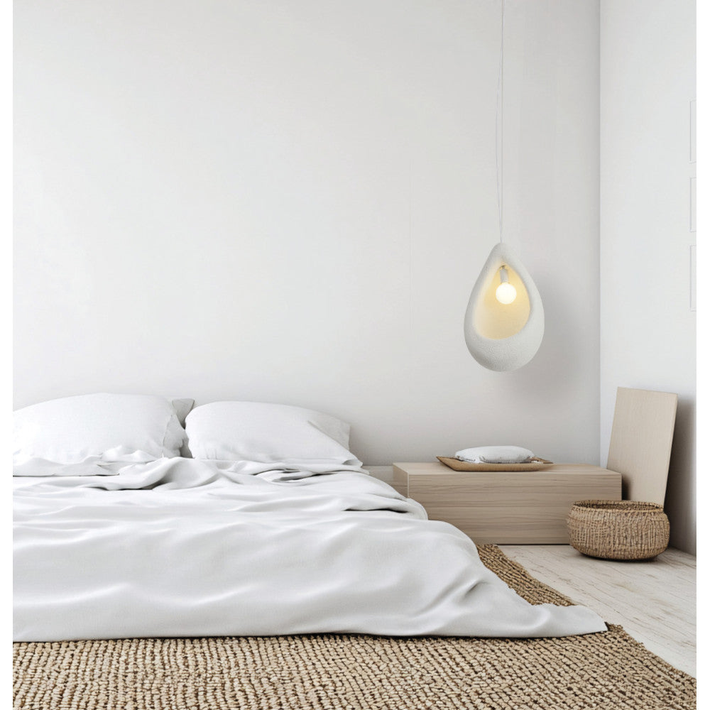 Ambiance chambre épurée : suspension blanche suspendue près d'un banc en bois, linge de lit blanc.