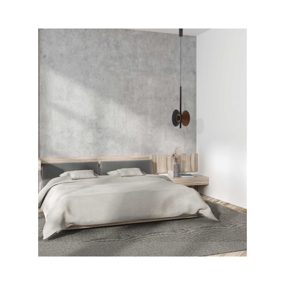Mise en ambiance dans une chambre, luminaire suspendu devant un mur gris béton