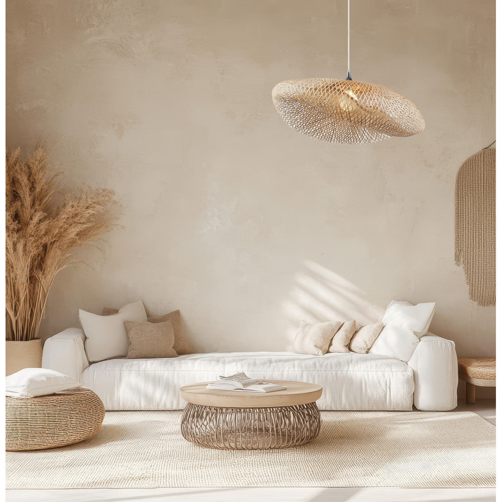 Mise en ambiance salon beige, suspension allumée au-dessus d'un canapé blanc et pampas.