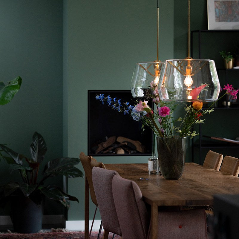 Deux suspensions en verre éclairées au-dessus d'une table dressée avec un bouquet de fleurs