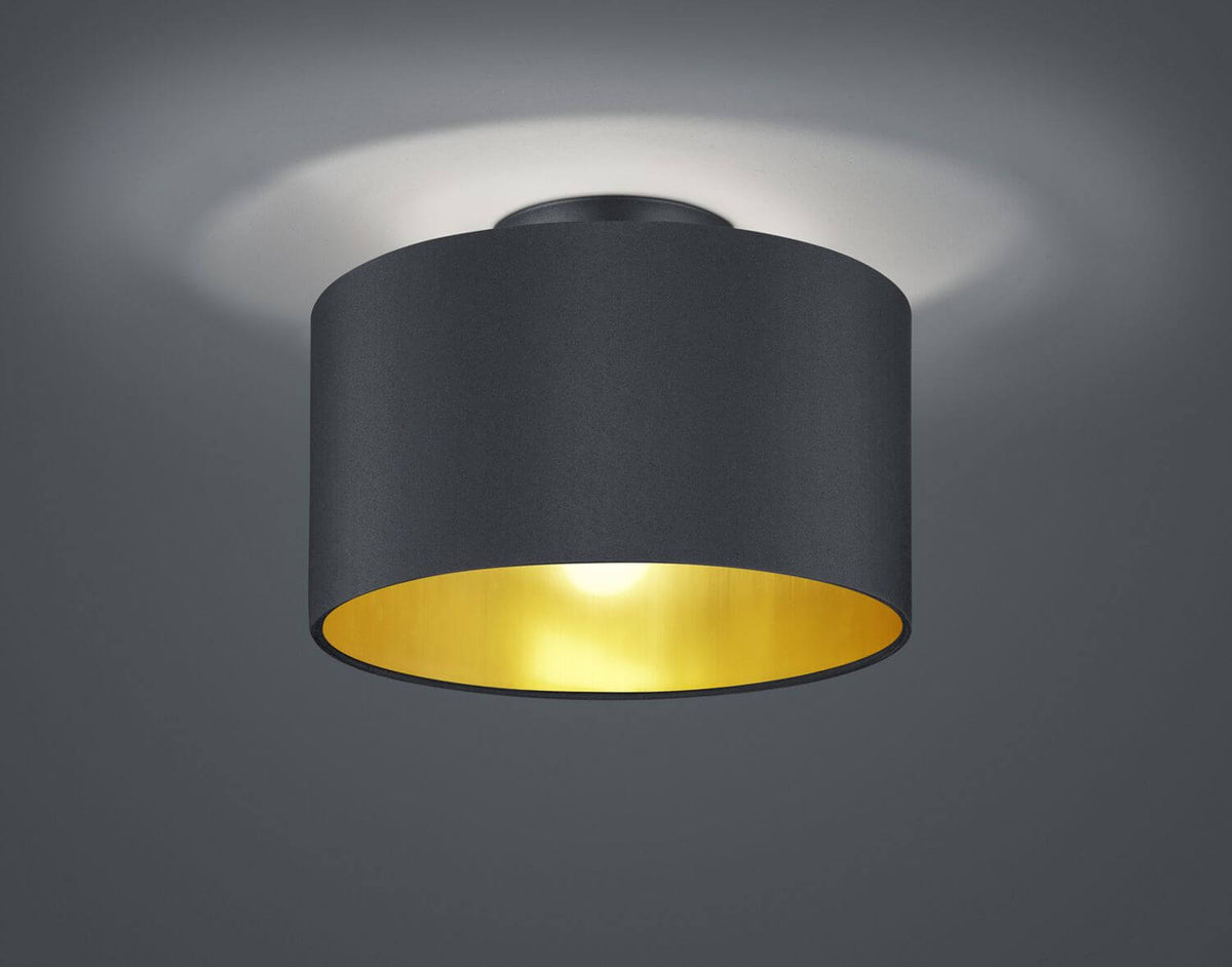Plafonnier cylindrique noir mat allumé, intérieur doré, présenté de face sur fond gris