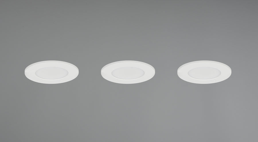 Trois spots encastrés allumés dans un plafond gris, halo lumineux diffus