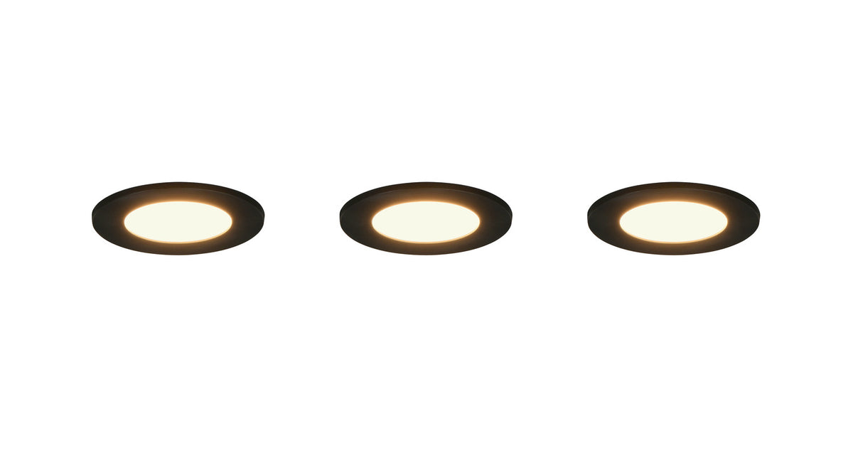 Trois spots encastrables noirs allumés diffusant une lumière chaude sur fond blanc